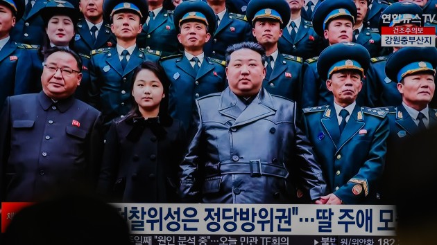 TV news at Seoul's Yongsan Railway Station shows North Korean leader Kim Jong Un (C) and his daughter (2nd from L, front row), believed to be named Kim Ju Ae, posing for a photo with scientists and engineers who contributed to the country's latest launch of a reconnaissance satellite, as he visited the National Aerospace Technology Administration in Pyongyang. (KIM Jae-Hwan/SOPA Images/LightRocket via Getty Images)
