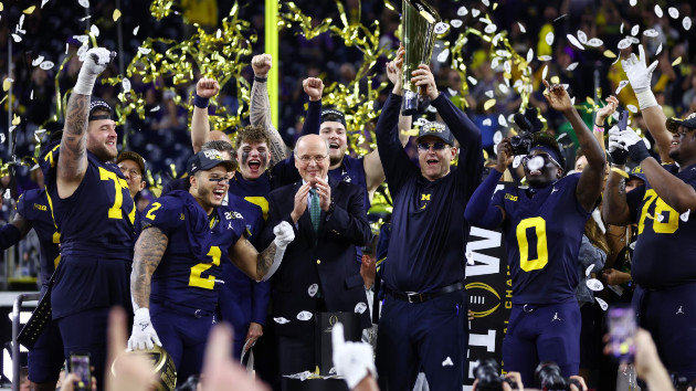 Head coach Jim Harbaugh of the Michigan Wolverines and his team react as he lifts the national championship trophy after defeating the Washington Huskies during the 2024 CFP National Championship game at NRG Stadium on Jan. 08, 2024 in Houston, Texas. (Maddie Meyer/Getty Images)
