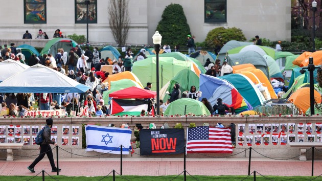 A man walks past Israeli and US flags alongside portraits of Israelis taken hostage by the militant Palestinian group Hamas in front of the pro-Palestinian encampment at Columbia University in New York on April 23, 2024. (CHARLY TRIBALLEAU/AFP via Getty Images)