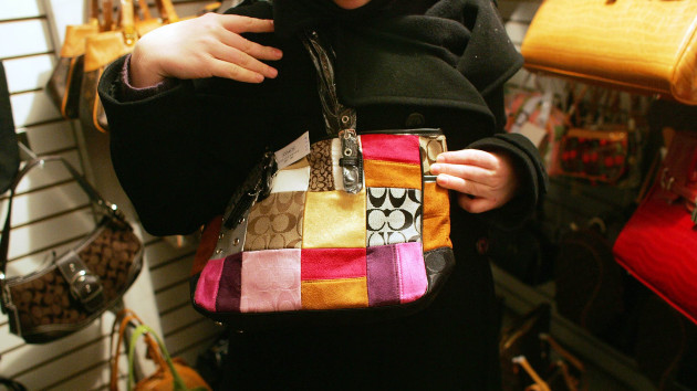 In this Feb. 1, 2006, file photo, an unidentified woman holds up a counterfeit Coach handbag in the back room of tourist shop in New York's Chinatown. (Bloomberg via Getty Images)