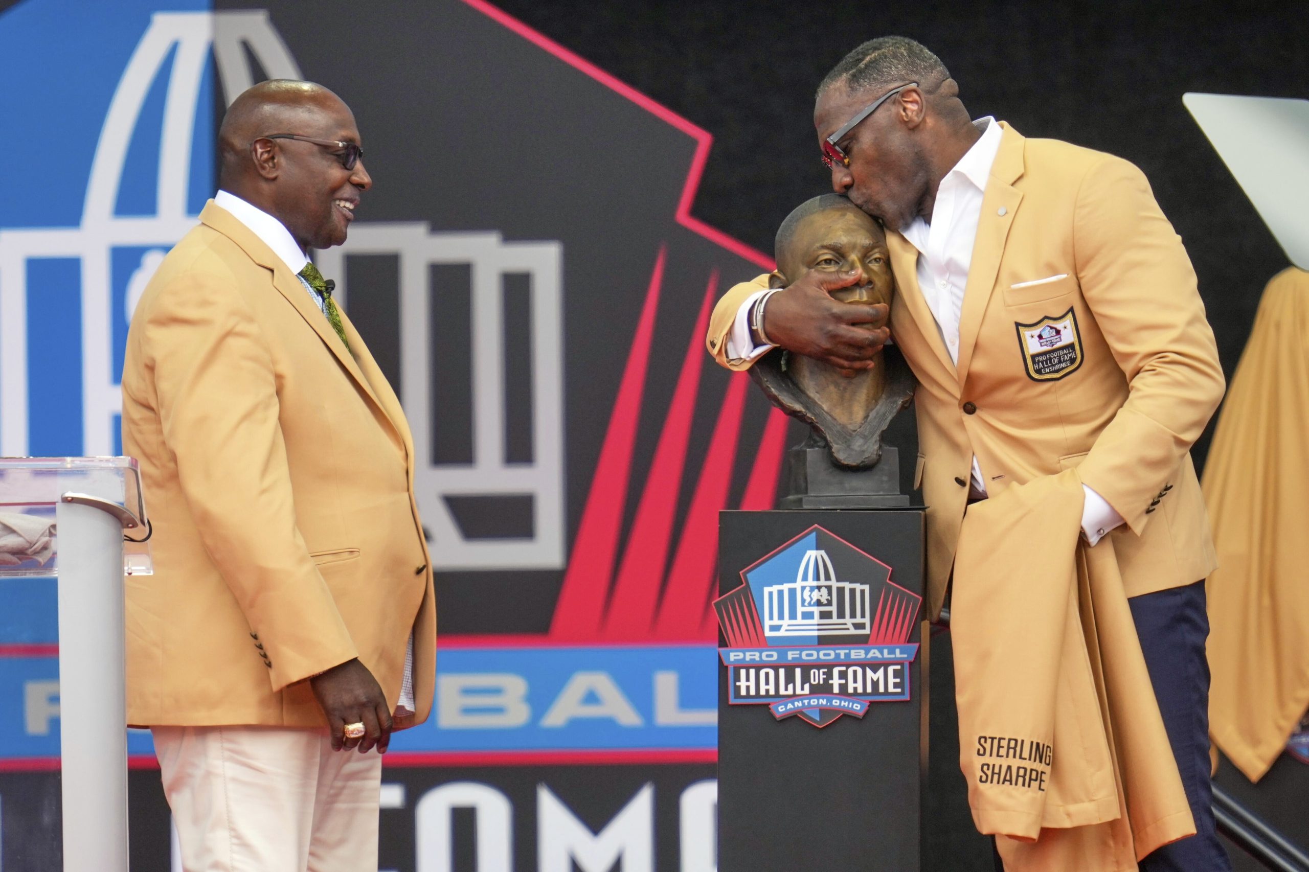 Sterling Sharpe gives fellow Pro Football Hall of Fame brother Shannon his gold jacket